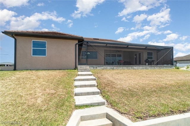 view of front of home featuring stucco siding, a lanai, and a front lawn