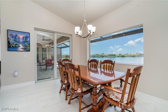 dining area featuring lofted ceiling, ceiling fan with notable chandelier, a water view, and baseboards