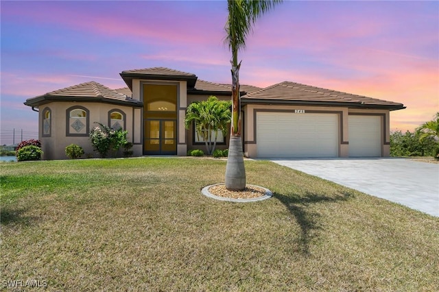 view of front of home with stucco siding, driveway, french doors, a front yard, and an attached garage