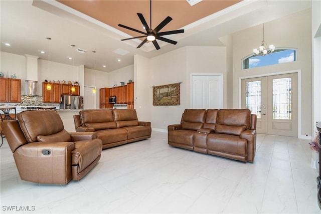 living room featuring recessed lighting, a high ceiling, a raised ceiling, french doors, and ceiling fan with notable chandelier