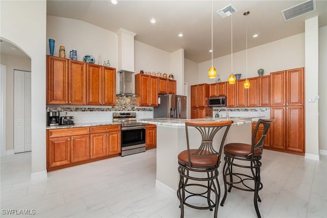 kitchen featuring marble finish floor, wall chimney range hood, stainless steel appliances, and visible vents