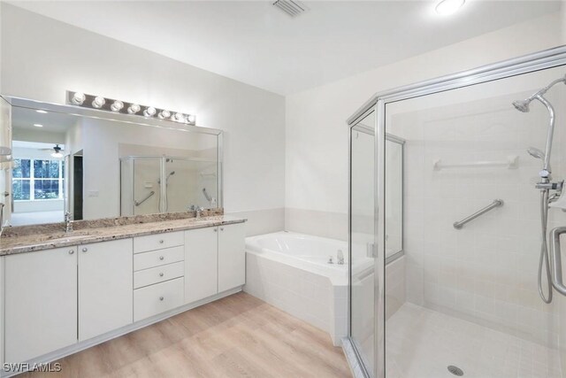 9040 Palmas Grandes Blvd Unit 101, Bonita Springs, FL 34135 - full bathroom with a stall shower, a garden tub, wood finished floors, double vanity, and a ceiling fan