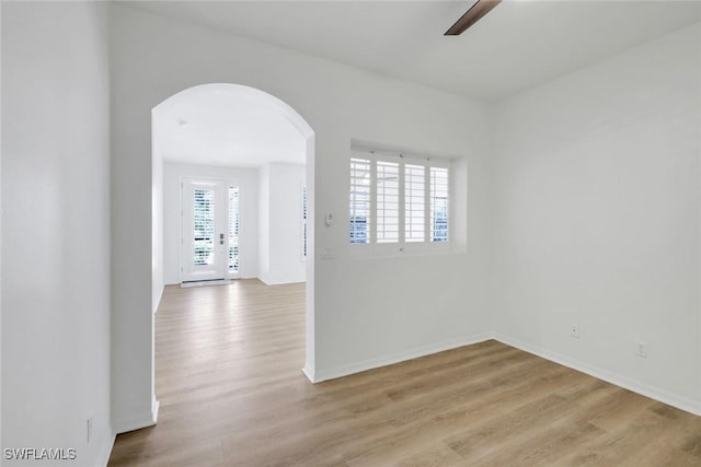 9040 Palmas Grandes Blvd Unit 101, Bonita Springs, FL 34135 - empty room featuring arched walkways, wood finished floors, a ceiling fan, and baseboards