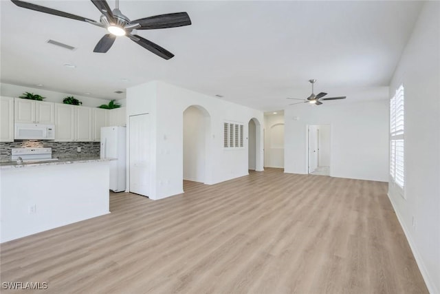 9040 Palmas Grandes Blvd Unit 101, Bonita Springs, FL 34135 - unfurnished living room featuring ceiling fan, arched walkways, and light wood-style flooring
