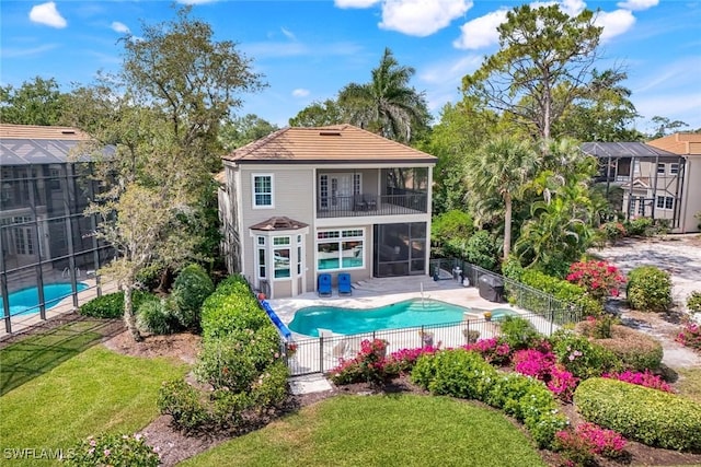 rear view of property featuring a patio area, a fenced in pool, a balcony, and fence
