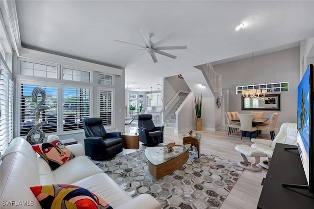 living room with stairway, wood finished floors, and ceiling fan with notable chandelier