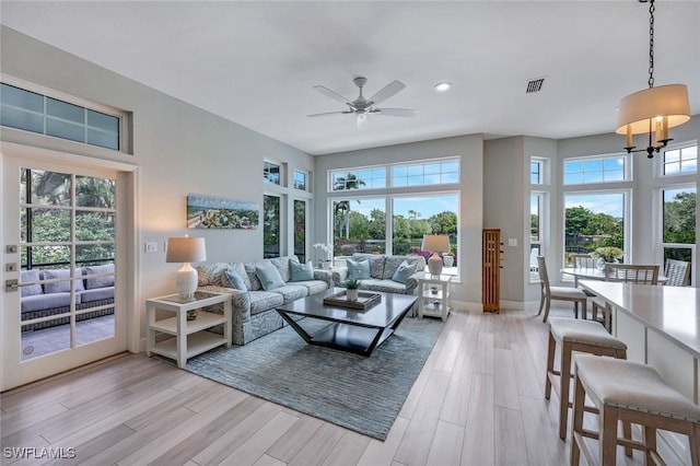 living room featuring ceiling fan with notable chandelier, recessed lighting, a wealth of natural light, and light wood-style floors
