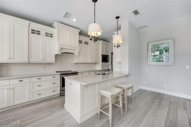 kitchen with a sink, decorative backsplash, a breakfast bar, visible vents, and electric range