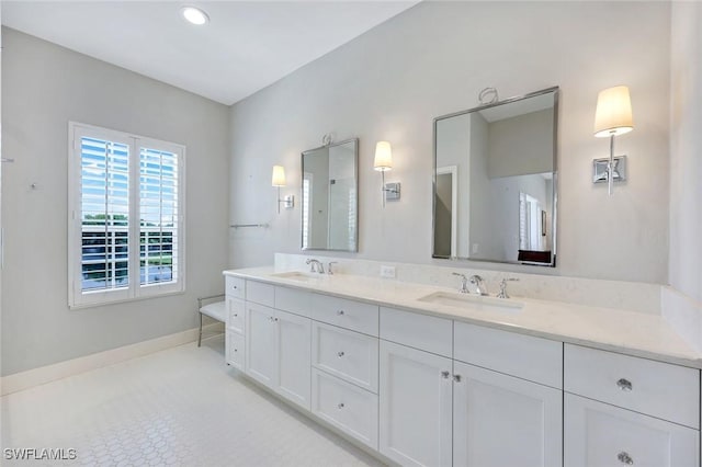 bathroom featuring baseboards, recessed lighting, double vanity, and a sink