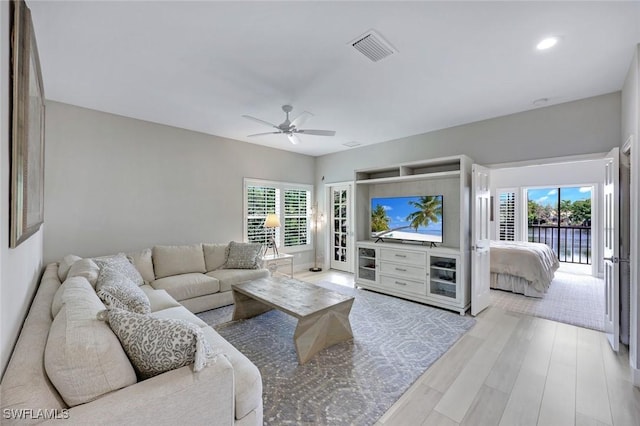 living area featuring light wood-type flooring, a ceiling fan, visible vents, and plenty of natural light