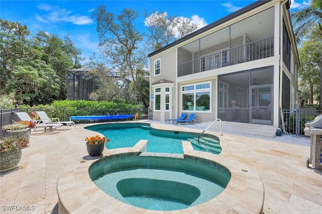 view of swimming pool with a pool with connected hot tub, a patio, and a sunroom