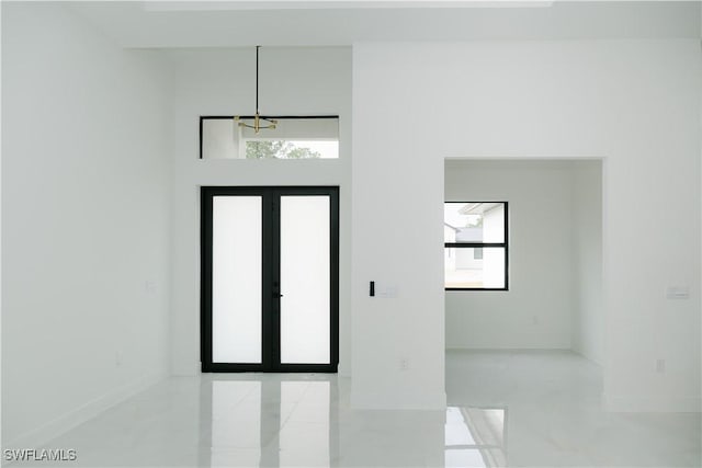 foyer entrance with baseboards, tile patterned flooring, and a notable chandelier