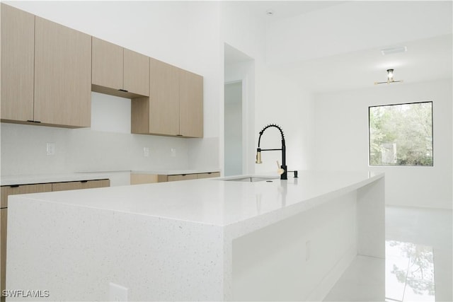kitchen with a sink, light countertops, modern cabinets, and a center island with sink