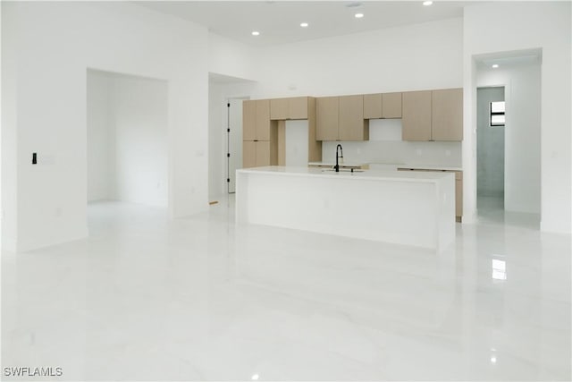 kitchen with recessed lighting, a sink, a kitchen island with sink, and light countertops