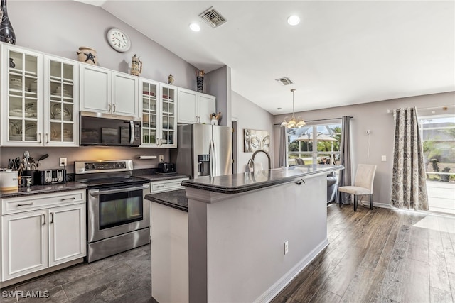 705 Columbus Blvd S, Lehigh Acres, FL 33974 - kitchen featuring stainless steel appliances, lofted ceiling, dark countertops, a kitchen island with sink, and white cabinetry