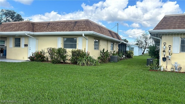 2213 Gardenia Way, Lehigh Acres, FL 33936 - view of property exterior with stucco siding, mansard roof, central AC, and a shingled roof