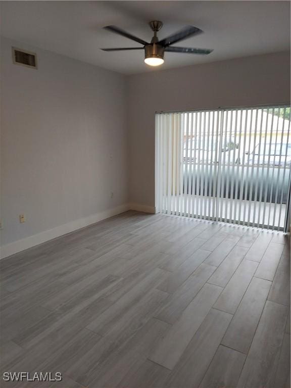 empty room with plenty of natural light, wood finished floors, visible vents, and ceiling fan