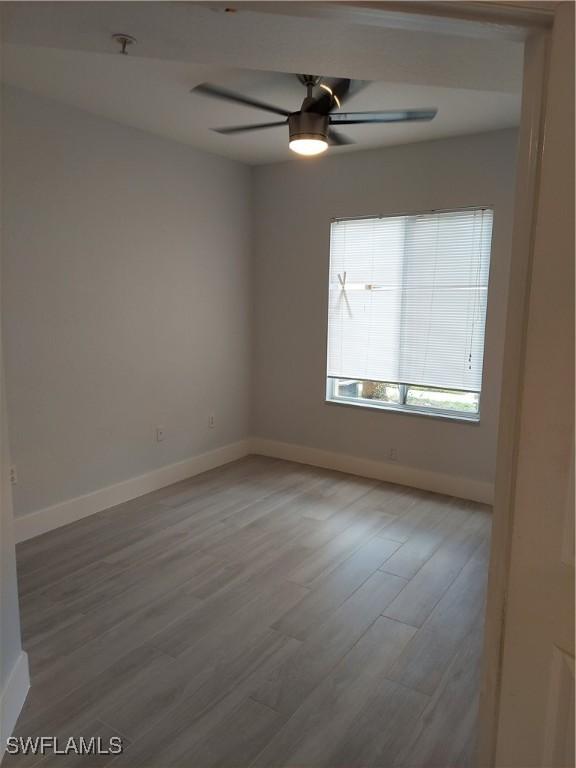 unfurnished room with ceiling fan, baseboards, and light wood-style floors