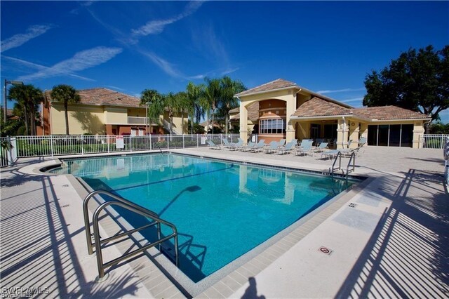 community pool with a patio area and fence