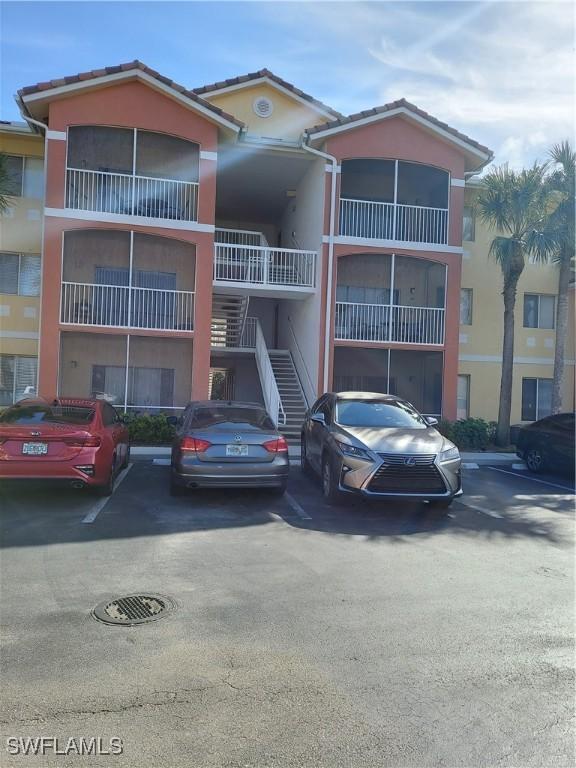 view of building exterior featuring stairs and uncovered parking