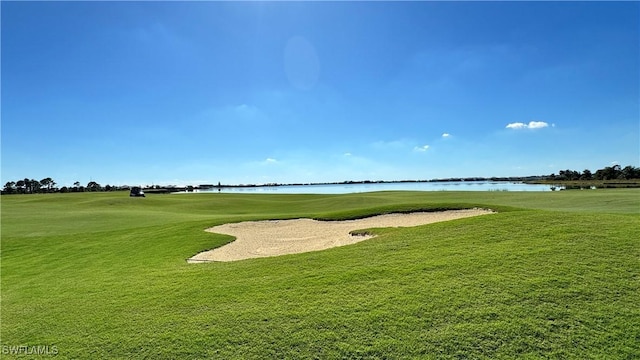 view of property's community featuring a yard, a water view, and view of golf course