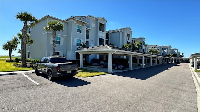 view of building exterior with covered and uncovered parking and a residential view