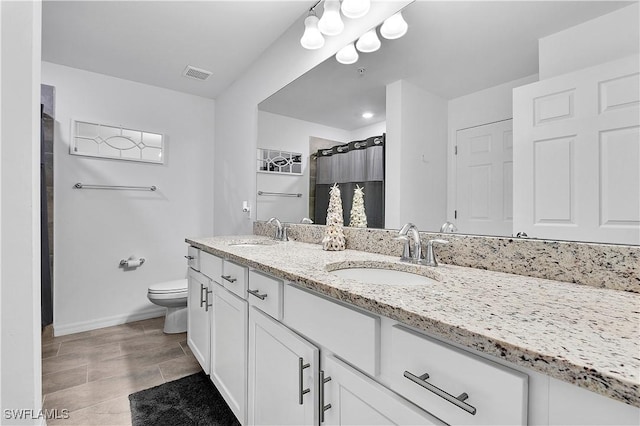 bathroom with double vanity, visible vents, toilet, and a sink