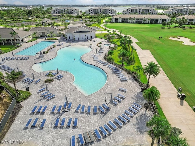 view of swimming pool with view of golf course and a yard
