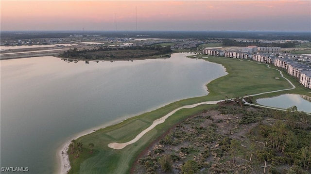 aerial view at dusk with a water view and view of golf course