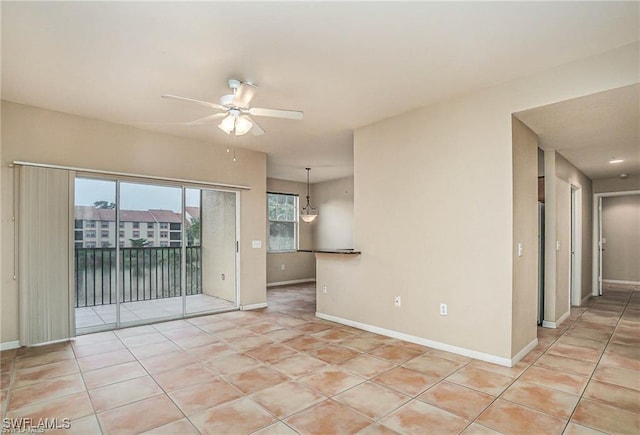 spare room featuring light tile patterned flooring, a ceiling fan, and baseboards