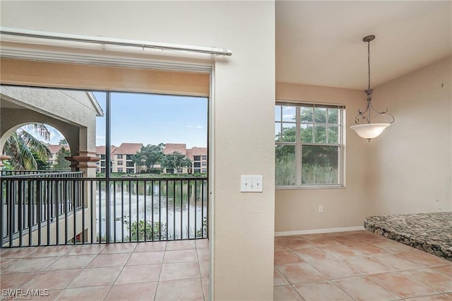 interior space with tile patterned floors, baseboards, and a water view
