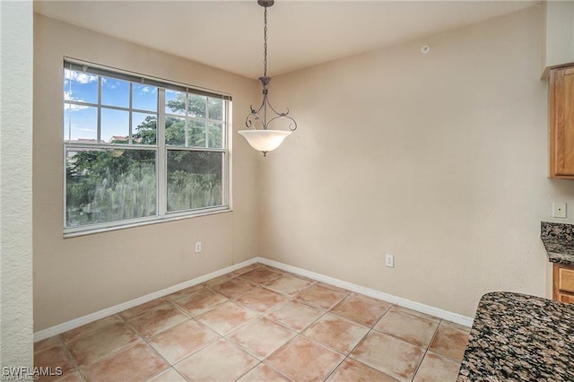 unfurnished dining area with baseboards and light tile patterned floors