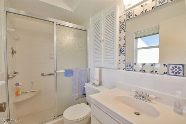 bathroom with toilet, a stall shower, backsplash, and vanity