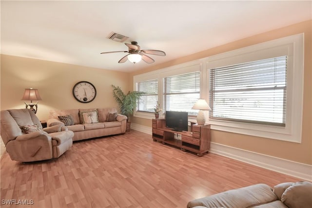 living room with visible vents, ceiling fan, light wood-style floors, and baseboards