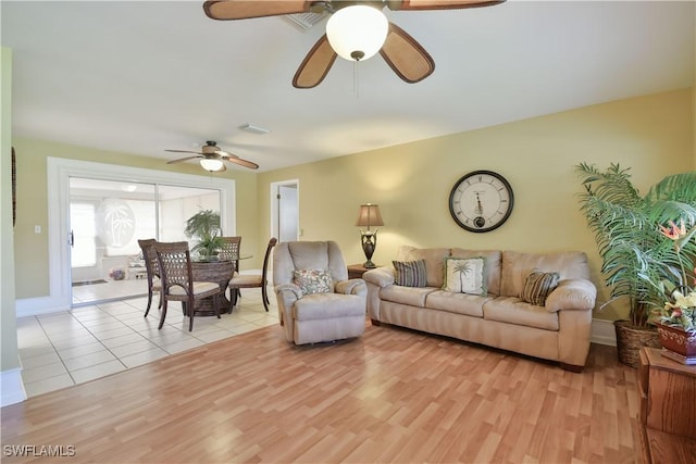 living room featuring light wood-style floors, a ceiling fan, visible vents, and baseboards