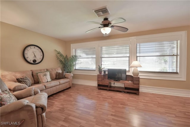 living area featuring baseboards, visible vents, light wood-type flooring, and ceiling fan