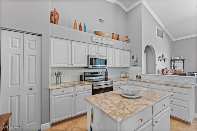2640 SW 29th Ave, Cape Coral, FL 33914 - kitchen featuring stainless steel appliances, crown molding, white cabinetry, a peninsula, and a center island