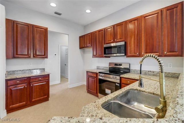 4220 12th Ave SE, Naples, FL 34117 - kitchen with a sink, light stone counters, stainless steel appliances, and reddish brown cabinets