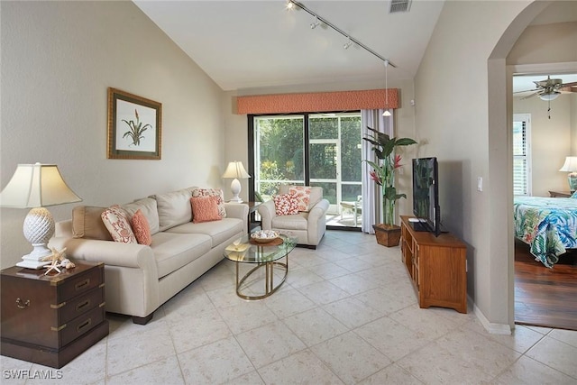 living room with arched walkways, light tile patterned flooring, lofted ceiling, ceiling fan, and rail lighting