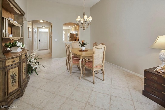 dining space with light tile patterned floors, arched walkways, a chandelier, and baseboards