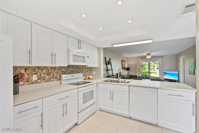 kitchen with a sink, visible vents, open floor plan, white appliances, and a peninsula