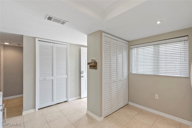 unfurnished bedroom with visible vents, baseboards, light tile patterned flooring, recessed lighting, and two closets