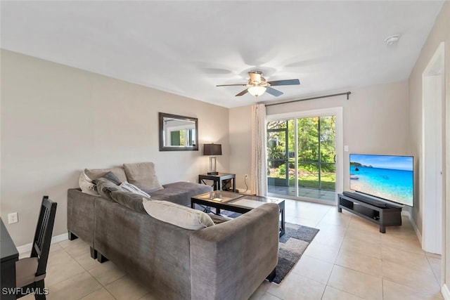 living area featuring light tile patterned flooring, a ceiling fan, and baseboards