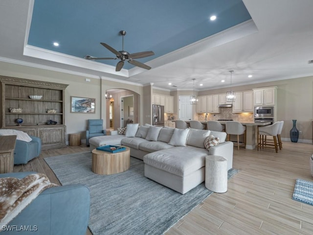9459 Campanile Cir, Naples, FL 34114 - living area with a raised ceiling, arched walkways, a ceiling fan, crown molding, and recessed lighting
