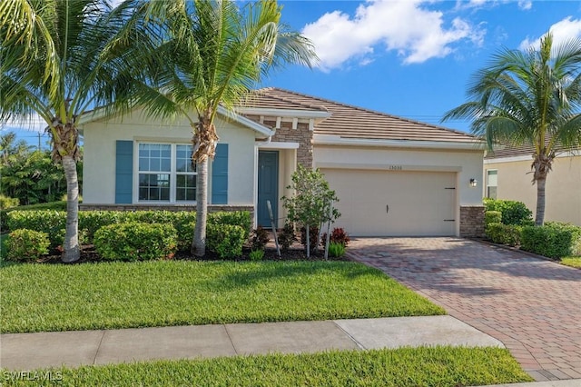 15030 Cortona Way, Fort Myers, FL 33908 - view of front of property with stucco siding, an attached garage, decorative driveway, and stone siding