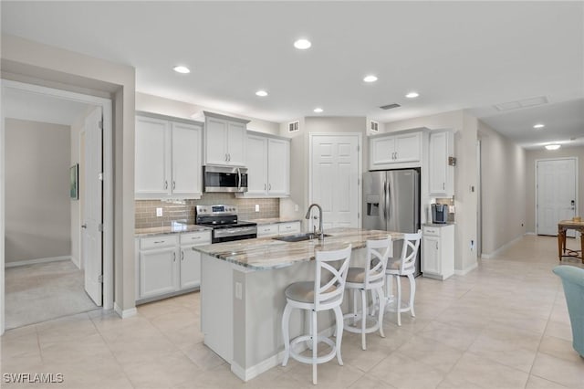 15030 Cortona Way, Fort Myers, FL 33908 - kitchen with a sink, tasteful backsplash, a kitchen bar, light stone counters, and appliances with stainless steel finishes