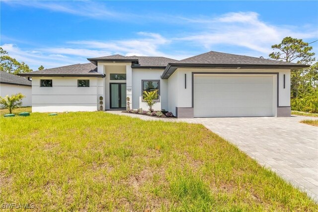 1025 Gladys St, Lehigh Acres, FL 33974 - prairie-style house with a shingled roof, stucco siding, decorative driveway, a front yard, and a garage