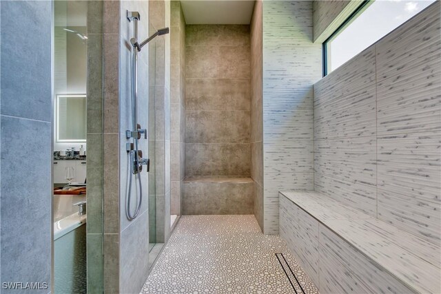 bathroom with a tile shower, tile walls, and tile patterned flooring