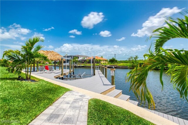 dock area with boat lift, a water view, and a yard