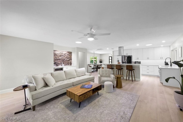 living room with recessed lighting, baseboards, a ceiling fan, and light wood-type flooring